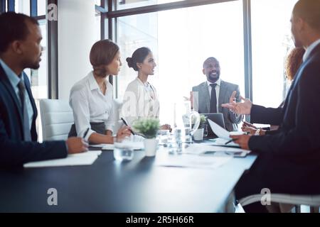 Seine Meetings halten alle motiviert. Ein Team von Profis, das eine Besprechung im Vorstandssaal bei der Arbeit abhält. Stockfoto