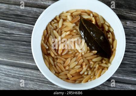 Nahöstliche ägyptische Pasta-Suppe, auch bekannt als Shorbet Lesan El Asfour, traditionelle ägyptische Komfortgerichte aus Orzo Pasta, Butter und Oliven Stockfoto