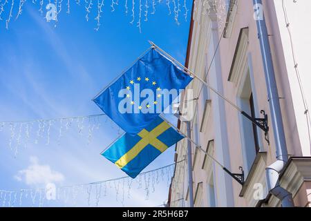 Die Flagge der Europäischen Union und die Flagge Schwedens flattern im Wind an der Wand des Gebäudes Stockfoto