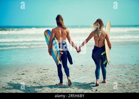 Wir surfen zusammen. Rückblick auf ein junges Paar, das auf die perfekte Welle wartet. Stockfoto