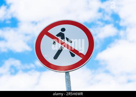 Ein Straßenschild mit der Aufschrift „kein Fußgängerverkehr“ vor einem grauen Himmelshintergrund. Das Schild ist mit einem weißen Kreis mit einem roten Rahmen und einer Zahl von einem per gekennzeichnet Stockfoto