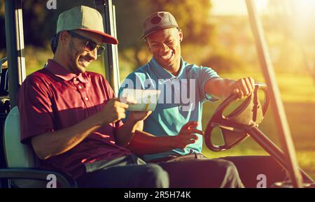 Das Leben zu leben. Zwei Golfer, die in einem Wagen auf einem Golfplatz reiten. Stockfoto