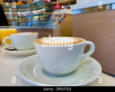 Ein herrliches Nahbild mit zwei dampfenden Tassen sattem und cremigem Cappuccino in einem authentischen italienischen Café. Das fesselnde Bild zeigt sich Stockfoto