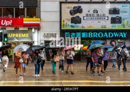 Gewöhnliche Leute aus Hongkong, die Während Eines Gewitters Eine Straße überqueren, Causeway Bay, Hongkong, China. Stockfoto