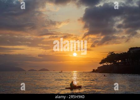 Silhouetten von Menschen in Kanus bei Sonnenaufgang am Copacabana-Strand in Rio de Janeiro, Brasilien. Stockfoto
