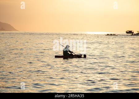 Silhouetten von Menschen in Kanus bei Sonnenaufgang am Copacabana-Strand in Rio de Janeiro, Brasilien. Stockfoto