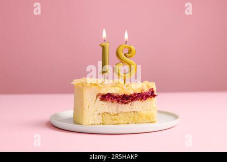 Geburtstagsparty zum 18. Geburtstag. Köstlicher Kuchen mit zahlenförmigen Kerzen auf pinkfarbenem Hintergrund Stockfoto