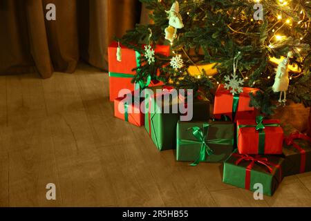 Wunderschön verpackte Geschenkboxen unter dem Weihnachtsbaum drinnen Stockfoto