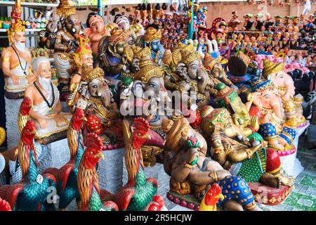 Farbenfrohe hinduistische und buddhistische Statuen des elefantengottes Ganesha, Hähne und heilige Männer zum Verkauf in einem Geschäft in Lom Sak, Phetchabun, Thailand Stockfoto