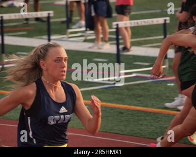 Highschool-Sprinter kämpfen um ein 400 Meter langes Staffelrennen. Entschlossenheit und Stärke werden auf den Flächen der Mitbewerber angegeben. Stockfoto