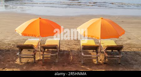 Leere Sonnenliegen mit Sonnenschirmen am Sandstrand der tropischen Insel Sri Lanka. Schöner sonniger Tag. Stockfoto