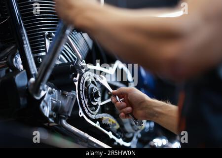 Ein männlicher Mechaniker repariert den Amotorradmotor mit einem Schraubenschlüssel im Service-Center Stockfoto