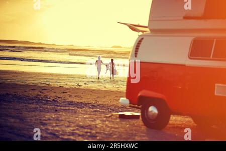 Liebe ist der Schlüssel zum Glück. Rückblick auf ein junges Paar, das am Strand zum Wasser rennt. Stockfoto