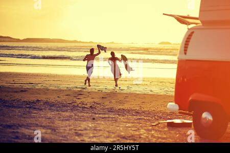 Geh dahin, wo die Liebe ist. Rückblick auf ein junges Paar, das am Strand zum Wasser rennt. Stockfoto