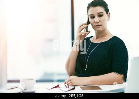 Sie ist immer bereit und in der Lage, die Bedürfnisse ihrer Kunden zu erfüllen. Eine junge Geschäftsfrau, die an ihrem Schreibtisch in einem Büro arbeitet. Stockfoto