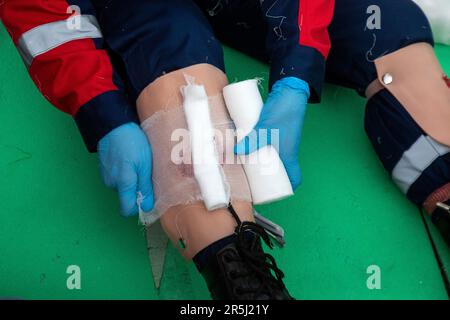 Moskau, Russland. 2. Juni 2023. Ein Rettungsschwimmer zeigt erste Hilfe, indem er einen Verband an einem verletzten Bein in Moskau anlegt Stockfoto