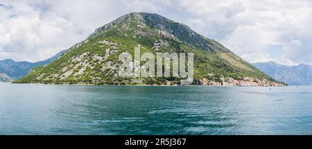 Einer der Berge, die die Bucht von Kotor säumen, ragt hoch über dem hübschen Dorf Perast in Montenegro. Stockfoto