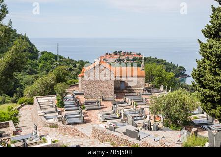 Das Kloster Praskvica und sein Friedhof wurden im Mai 2023 über dem Sveti Stefan an an der Küste Montenegros abgebildet. Stockfoto