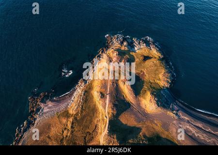 Im Sommer bietet sich auf der atlantischen Halbinsel Island ein Blick von oben auf die Straße zum Leuchtturm an der Küste Stockfoto