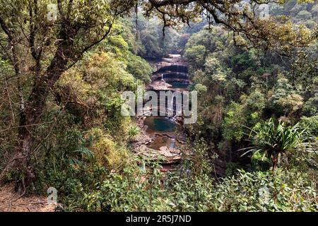 Die spektakulären dreistufigen Wei Sawdong-Wasserfälle stürzen in eine klare türkisfarbene Lagune, umgeben von üppigem tropischem Wald in Meghalaya, Indien. Stockfoto