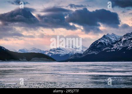 Wunderschöne Winterlandschaft bei Sonnenaufgang über felsigen Bergen und gefrorenem See im Abraham Lake im Jasper National Park, ab, Kanada Stockfoto