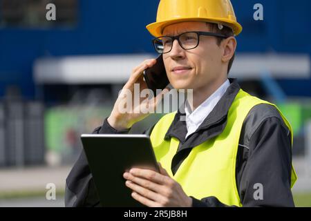 Mitarbeiter mit Telefon und digitalem Tablet im Hintergrund eines Logistikzentrums Stockfoto