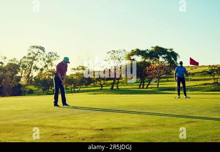 Gute Spieler üben, bis sie es richtig machen. Zwei Freunde spielen eine Runde Golf auf einem Golfplatz. Stockfoto