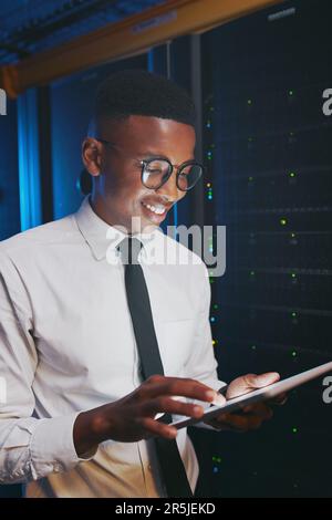 Ich habe alle Daten, die ich brauche. Ein junger IT-Spezialist, der allein im Serverraum steht und ein digitales Tablet verwendet. Stockfoto