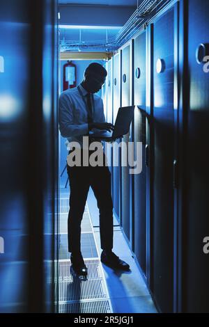 Wir arbeiten hart daran, Ihre Informationen zu schützen. Ein junger Mann, der in einem IT-Serverraum arbeitet. Stockfoto