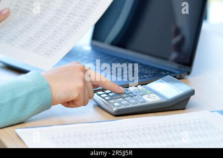 Buchhalter, der mit einem Taschenrechner auf einem Schreibtisch im Büro rechnet Stockfoto