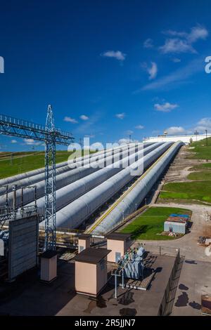 Sergijew Posad, Russland - 18. Mai 2022: Wasserleitungen des Wasserkraftwerks Zagorskaya auf blauem Himmel und Elektroturm (links) Stockfoto