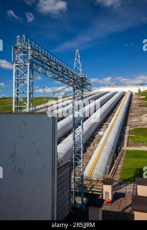 Wasserkraftwerksleitungen und elektrische Türme am blauen Himmel. Stockfoto