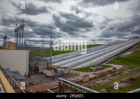 Rohre von Wasserkraftwerken und elektrische Unterstation auf grauem Hintergrund Stockfoto