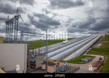 Wasserkraftwerksrohre anв Elektrounterstation vor grauem Himmel Stockfoto