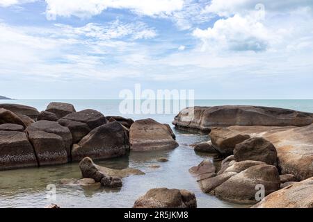 Eine Felsformation vor einem Strand von phuket mit stilem Wasser Stockfoto