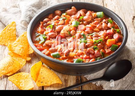 Mexikanische Charrobohnen mit Pintobohnen, Speck, Schinken, Chorizo, Chili-Paprika, Tomaten und Gewürze auf der Schüssel auf dem Tisch. Horizontal Stockfoto