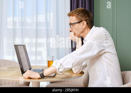 Mann mittleren Alters, der von zu Hause aus ein individuelles Einkommensteuerformular einreicht Stockfoto