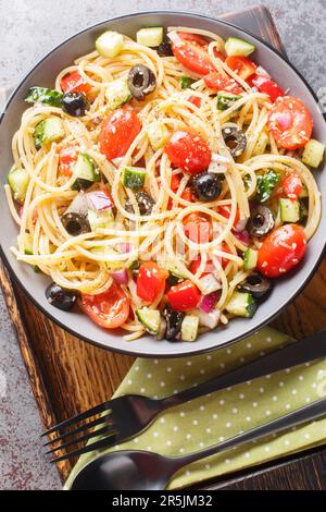 Der kalte italienische Spaghetti-Salat enthält frisches Gemüse und jede Menge leckeres Dressing auf der Schüssel auf dem Tisch. Vertikale Draufsicht von oben Stockfoto