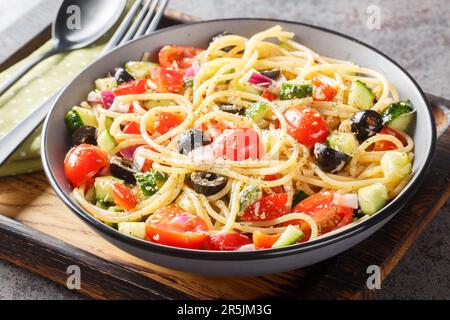 Spaghetti-Pasta mit Oliven, Tomaten, Zwiebeln, Gurken und Paprika in einer Schüssel auf dem Tisch. Horizontal Stockfoto