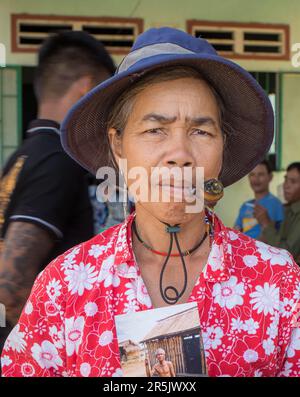 Eine Frau mittleren Alters aus der ethnischen Minderheit Kontum Province, Vietnam, raucht eine Pfeife, da sie ein Foto von ihrem Vater Holdin vor 30 Jahren besitzt Stockfoto