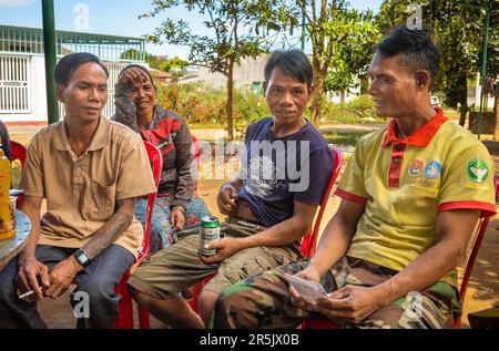 Drei Männer und eine Frau aus der ethischen Minderheit sitzen zusammen in ihrem Dorf Dak Me, Bo Y Commune, Ngoc Hoi District, Kontum Province in Th Stockfoto