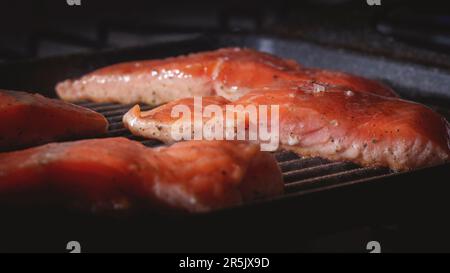 Roher Lachs wurde gerade zum Kochen auf einen Grill gestellt. Gewürzt mit Salz und Kräutern Stockfoto