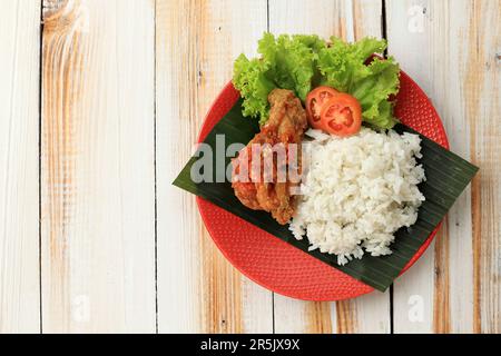 Top View Nasi Ayam Penyet Sambal Bawang, Reis mit gebratenem Hähnchen mit würziger Knoblauchsauce. Kopierbereich für Text auf weißem Holztisch Stockfoto