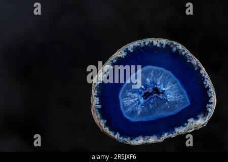 Ein blaues Achat mit einem schwarz schattierten Hintergrund. In der Mitte des Minerals können Sie die kleinen Kristalle sehen, die sich natürlich im Geode bilden. Stockfoto