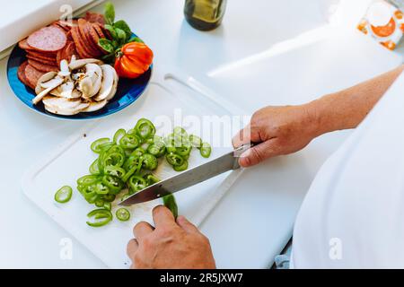 Die Hände des Mannes schneiden Pfeffer aus der Nahaufnahme von oben in Scheiben Stockfoto