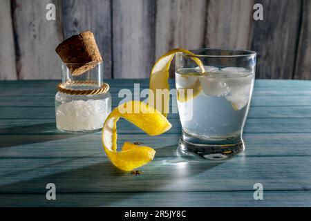 Ein Glas Zitronenwasser Kefir mit Kefir-Körnern im Hintergrund in einem Glasgefäß Stockfoto