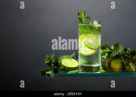 Mojito mit Eis, Limette und Minze. Eisgetränk in einem beschlagenen Glas auf schwarzem Hintergrund. Speicherplatz kopieren. Stockfoto