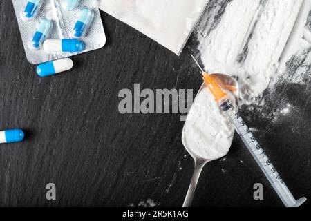 Drogenmissbrauch. Harte Drogen auf dunklem Tisch. Draufsicht. Stockfoto