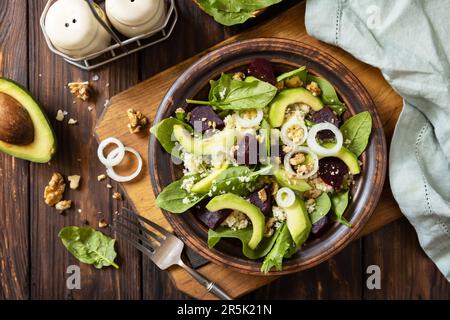 Vegane Speisen, kalorienarme Diät. Couscous mit Avocado, Rüben, grünen Bohnen, Spinat auf einem rustikalen Holztisch. Blick von oben. Stockfoto