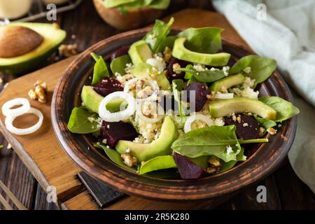 Vegane Speisen, kalorienarme Diät. Couscous mit Avocado, Rüben, grünen Bohnen, Spinat auf einem rustikalen Holztisch. Stockfoto